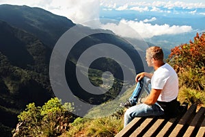 Man relaxes on the edge of the cliff . Plateau ` End of the World ` , Sri Lanka