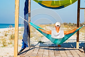 Man relaxes in a hammock on abandoned bungalow veranda