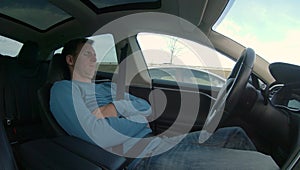 Man relaxes while his high tech self driving car navigates through rush hour