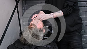 A man relaxes when he washes his hair in a barber shop. The master barber washes the client& x27;s head.