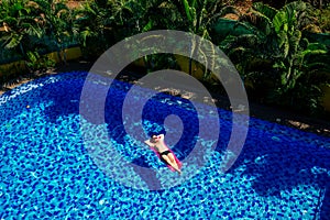 Man relaxing on the air bed inflatable pink mattress in the swimming pool vacation