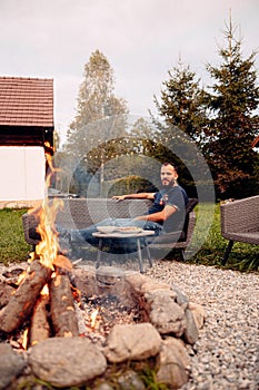 Man relaxing by a backyard fire pit