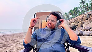 Man relaxing on a beach chair listening music with headphones eyes closed enjoying a peaceful moment on a sandy beach