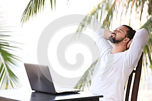 Man relaxing on the beach with laptop, freelancer workplace, dream job