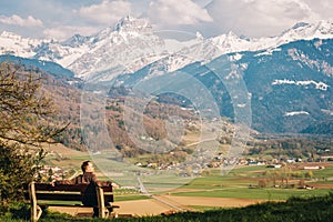 Man relaxing on the bench, admiring  swiss Alps