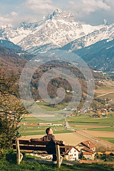 Man relaxing on the bench, admiring  swiss Alps
