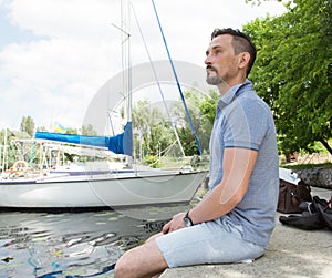 A Man relaxing dreaming and enjoying the view on nature and lake. Handsome young man posing outdoors in port