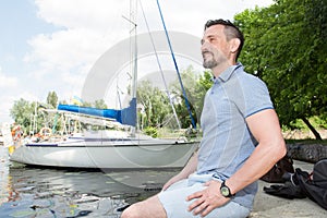 Man relaxing and enjoying the view in nature and lake. Handsome man breathing outdoors on boat background.