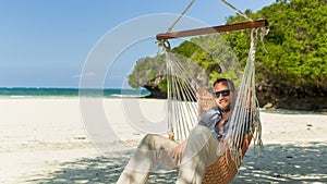 Man relaxing in a hammock on the beach on holidays.