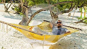 Man relaxing in a hammock on the beach on holidays.