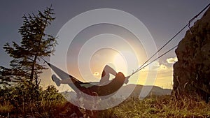 Man relaxing in hammock at sunset in the mountains