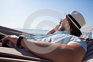 Man relaxing on hammock and talking on mobile phone on the beach