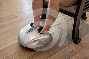 Man relaxing while having a foot massage on a machine at home