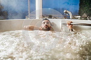 Man relaxing at home in the hot tub bath ritual.Spa day moment in modern bathroom indoors jacuzzi tub.Body care.Good personal