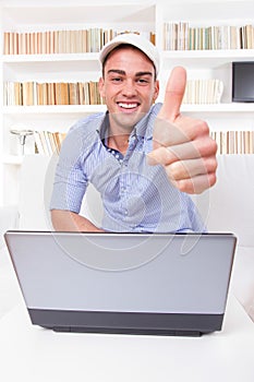 Man relaxing at home with laptop computer showing thumbs up