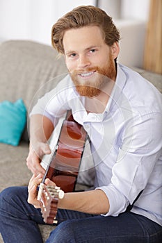 man relaxing at home playing guitar