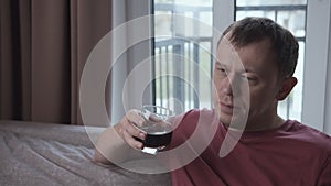 Man relaxing at home, sitting on sofa and drinking from a glass, relaxation concept