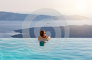 Man relaxing in infinity swimming pool, looking at the sea view