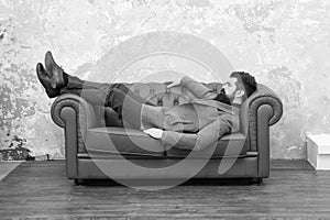 Man relaxing on luxurious leather couch, furniture store concept