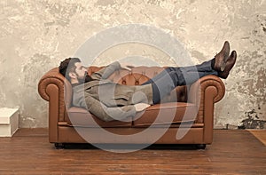 Man relaxing on luxurious leather couch, furniture store concept