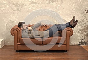 Man relaxing on luxurious leather couch, thoughtful mood concept