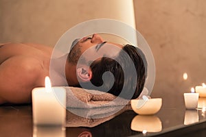 Man relaxing on massage table at Asian spa and wellness center