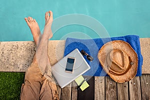 Man relaxing near swimming pool with computer