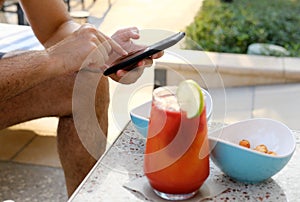 Man Relaxing with Phone by Refreshing Poolside Drink