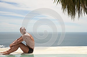 Man Relaxing By Poolside At Resort