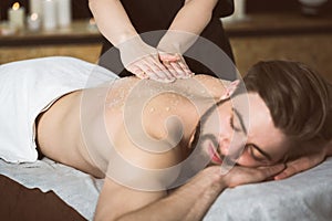 Man relaxing during a salt scrub beauty therapy photo