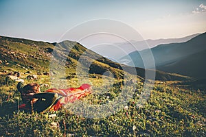 Man relaxing in sleeping bag enjoying sunset mountains