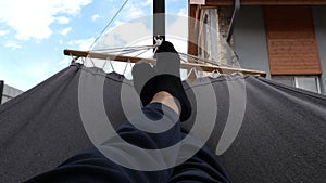 man relaxing in a slow swinging hammock, first-person view on feet