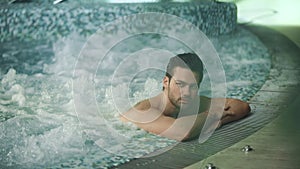 Man relaxing in spa on vacation. Male resting in jacuzzi at wellness center