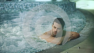 Man relaxing in spa on vacation. Male resting in jacuzzi at wellness center