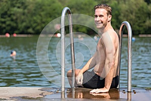 Man relaxing in the sun at public swimming pool