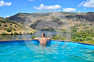 Man relaxing in a swimming pool looking the landscape