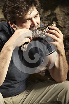 Man relaxing in wilderness and eating hunted fish