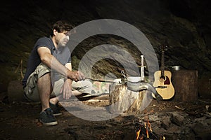 Man relaxing in wilderness and preparing hunted fish on fire