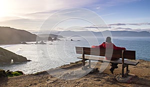 Man relaxing on a woden bench in Loiba Cliffs, Ortigueira, Spain photo
