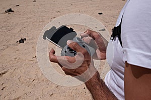 man with remote control flying drone on fuerteventura beach in unrestricted zone