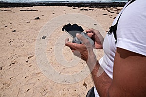 man with remote control flying drone on sandy beach in canary islands fuerteventura