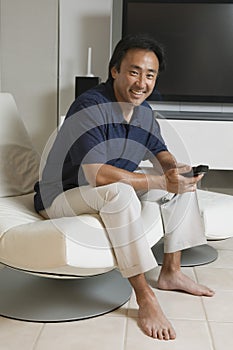 Man With Remote Control In Front Of Large TV Screen At Home