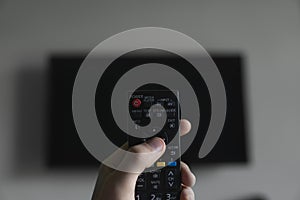 The man with the remote control in hand want switch on the TV and presses the button on the remote control. Remote