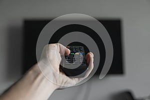 The man with the remote control in hand want switch on the TV and presses the button on the remote control. Remote