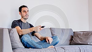 Man with remote control on sofe watching TV