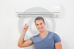 Man With Remote Control To Operate Air Conditioner