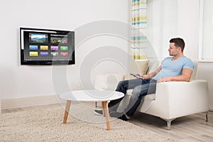 Man With Remote Control Watching Television At Home