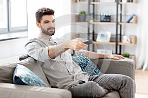 Man with remote control watching tv at home