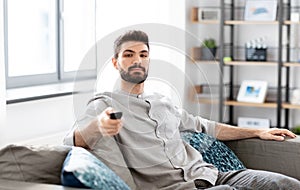 Man with remote control watching tv at home