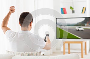 Man with remote watching motorsports on tv at home photo